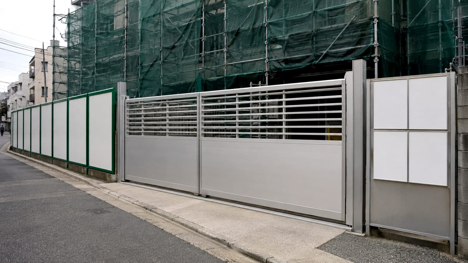 アルミゲートと仮囲い、防炎メッシュシート、法定表示板を設置した建築工事現場の入口のイメージ