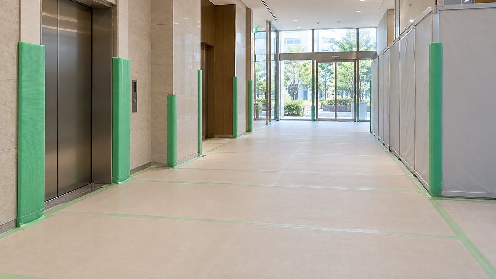 共用通路の床を養生し壁の角とエレベーター枠を保護した改修現場のイメージ