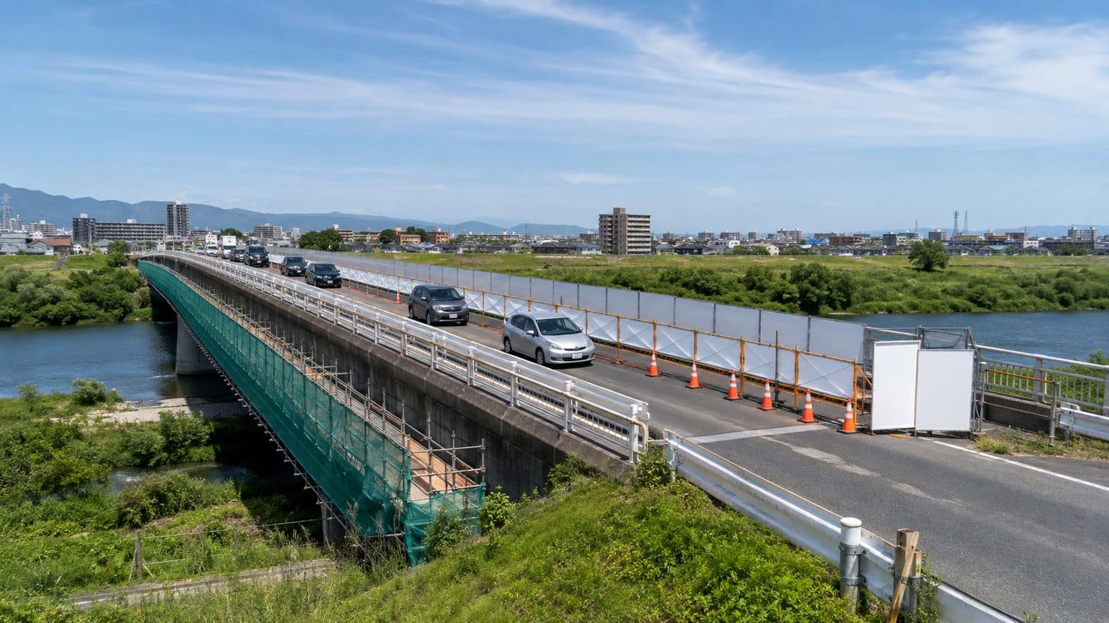 供用したまま片側車線を規制し、桁下に吊り足場を組んで補修している道路橋のイメージ